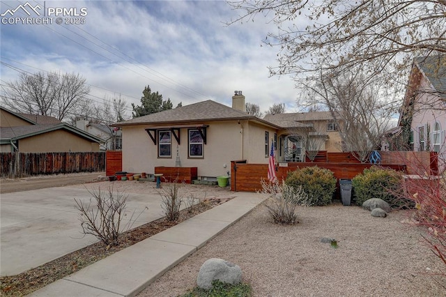 view of front of house featuring fence, concrete driveway, roof with shingles, stucco siding, and a chimney