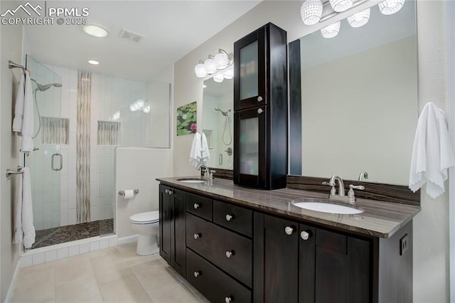 bathroom with toilet, a stall shower, double vanity, and a sink