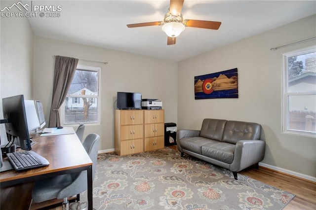 home office with light wood finished floors, a ceiling fan, and baseboards