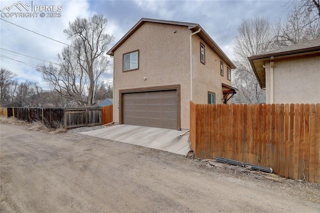 view of side of property featuring a garage, fence, and stucco siding