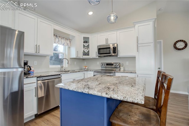 kitchen with a breakfast bar area, light wood-style flooring, stainless steel appliances, a sink, and white cabinetry