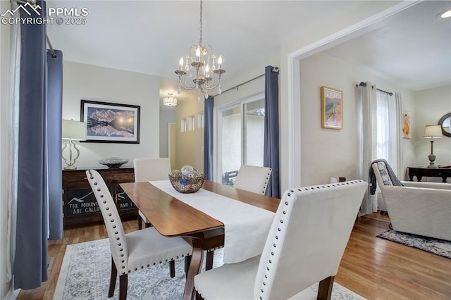 dining area featuring wood finished floors and an inviting chandelier