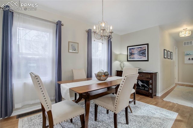 dining area featuring light wood-style floors, visible vents, baseboards, and an inviting chandelier