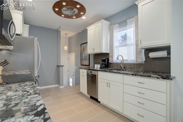 kitchen with decorative backsplash, appliances with stainless steel finishes, white cabinetry, a sink, and dark stone countertops