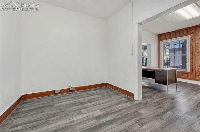 spare room with wooden walls, dark hardwood / wood-style floors, and a textured ceiling