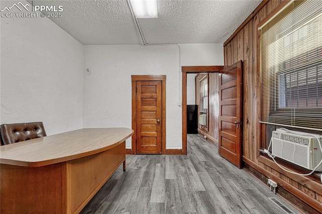 unfurnished office with cooling unit, hardwood / wood-style floors, and a textured ceiling