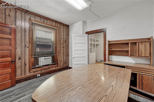 unfurnished office featuring wood-type flooring, cooling unit, a textured ceiling, and wooden walls