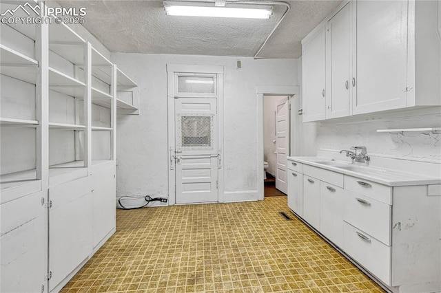 kitchen with sink, white cabinets, and a textured ceiling