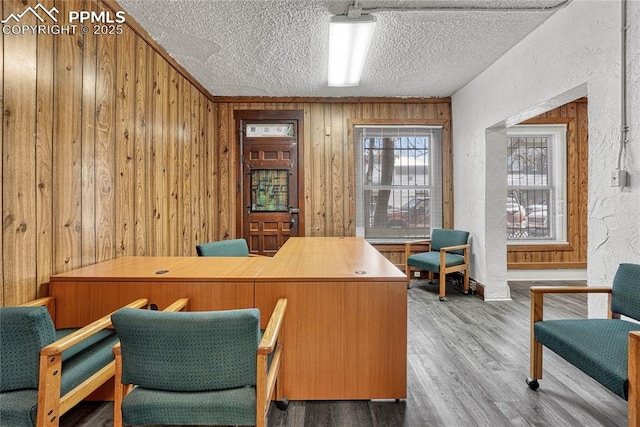 office area with a textured ceiling, wooden walls, and wood-type flooring