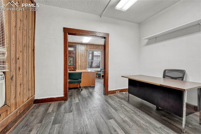 home office with wooden walls, dark hardwood / wood-style flooring, and a textured ceiling