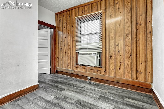 empty room with cooling unit, wooden walls, dark hardwood / wood-style floors, and a textured ceiling