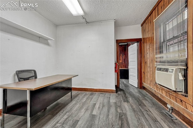 unfurnished office with dark wood-type flooring, cooling unit, a textured ceiling, and wooden walls