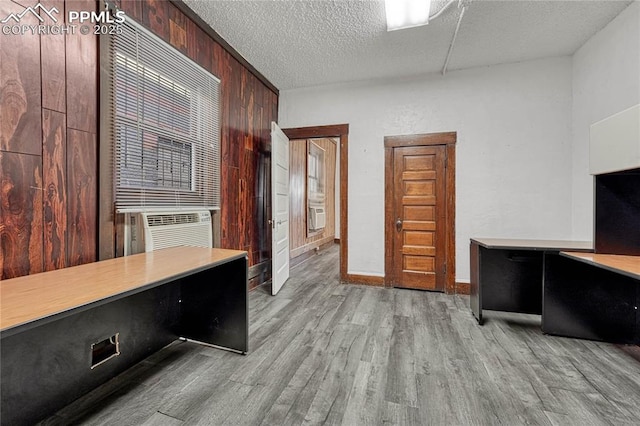 office area featuring wooden walls, a textured ceiling, and light wood-type flooring