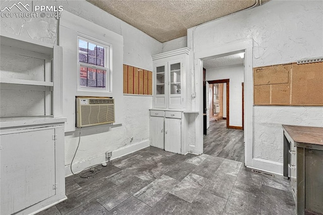 interior space featuring white cabinetry, a wall mounted air conditioner, dark hardwood / wood-style floors, and a textured ceiling