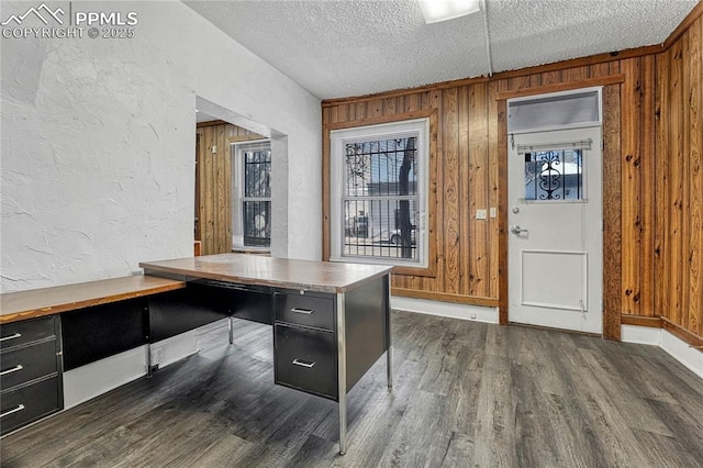 unfurnished office with dark wood-type flooring, a textured ceiling, and wood walls