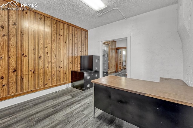 office area with hardwood / wood-style flooring, wooden walls, and a textured ceiling