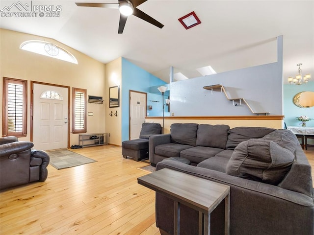 living room featuring ceiling fan with notable chandelier, lofted ceiling, and light hardwood / wood-style floors