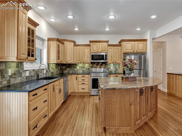 kitchen featuring light brown cabinetry, sink, a kitchen island, light hardwood / wood-style flooring, and stainless steel appliances