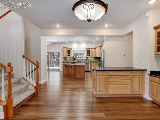 kitchen featuring kitchen peninsula, tasteful backsplash, light hardwood / wood-style flooring, and stainless steel appliances