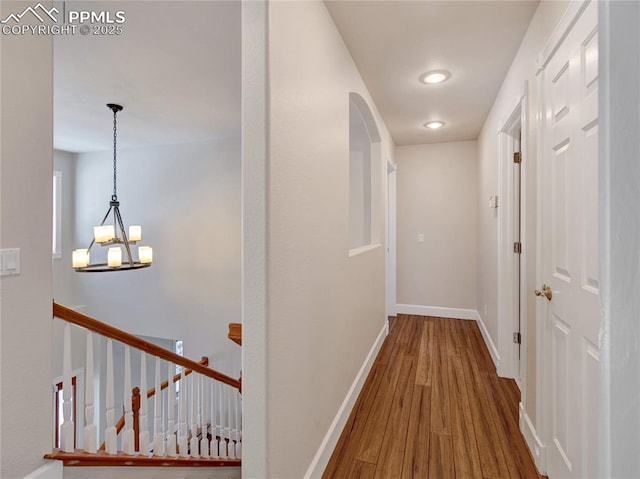 hallway with hardwood / wood-style floors and a notable chandelier