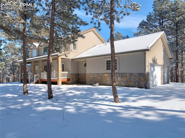 snow covered house with a porch and a garage