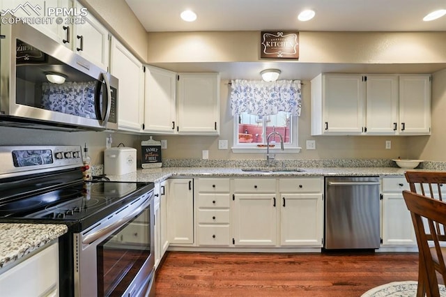 kitchen featuring sink, light stone counters, dark hardwood / wood-style floors, stainless steel appliances, and white cabinets