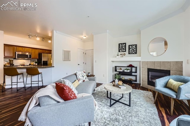 living room with a tile fireplace, dark hardwood / wood-style floors, and crown molding