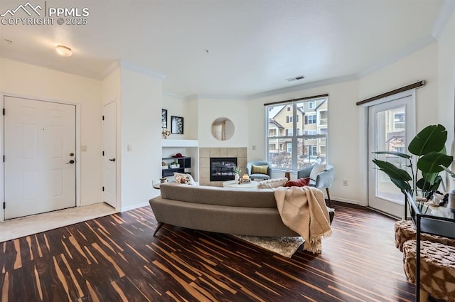 living room featuring a tile fireplace, crown molding, and hardwood / wood-style floors