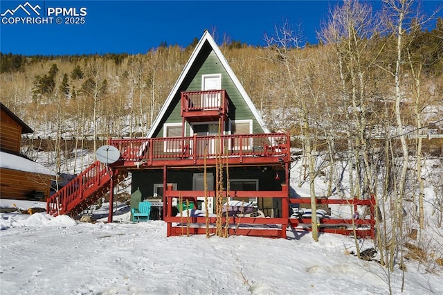 snow covered house featuring a deck