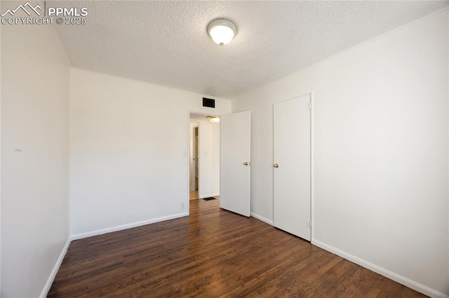 unfurnished bedroom with a textured ceiling and dark hardwood / wood-style flooring