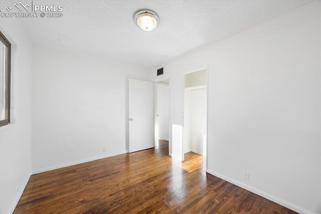 unfurnished bedroom with dark wood-type flooring, a textured ceiling, and a closet