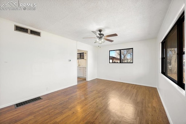 empty room with dark wood-type flooring, ceiling fan, and a textured ceiling