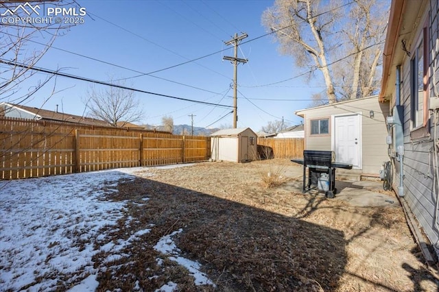 snowy yard featuring a storage shed