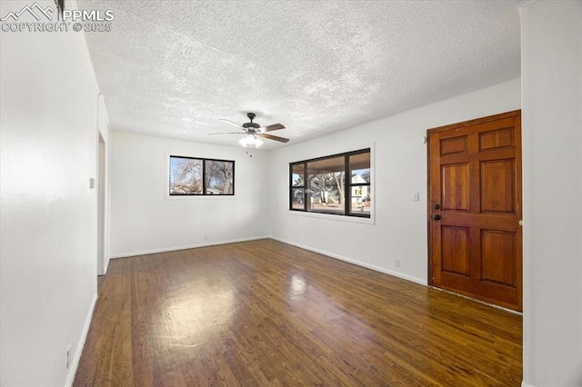 spare room featuring dark hardwood / wood-style flooring, a wealth of natural light, and a textured ceiling