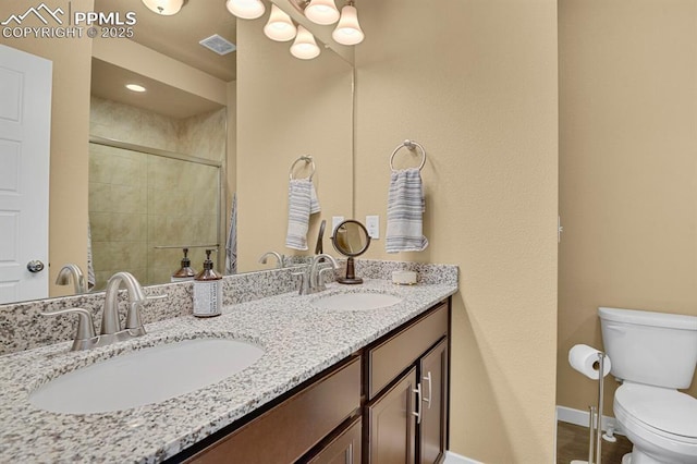 bathroom with vanity, a shower with door, and toilet