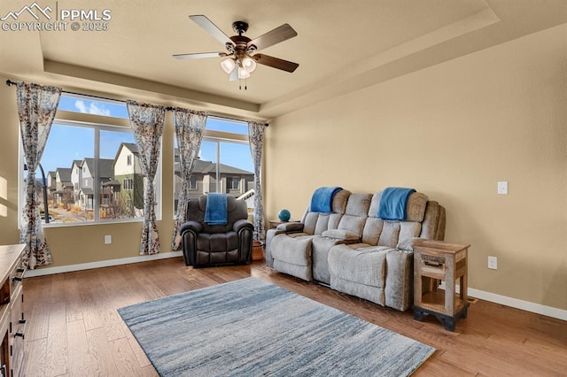 sitting room with hardwood / wood-style flooring, ceiling fan, and a raised ceiling