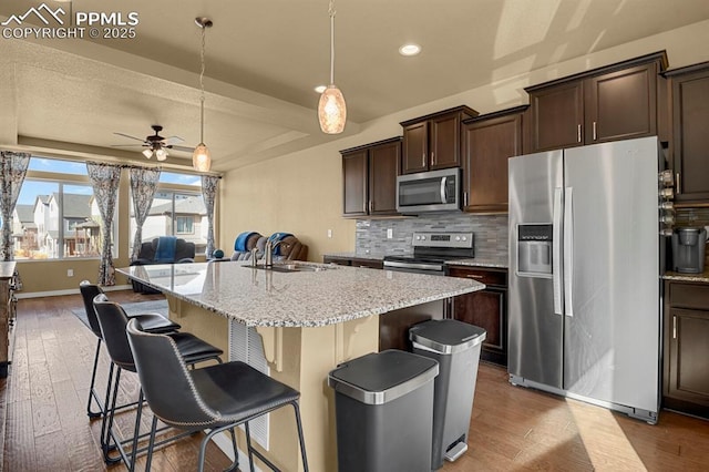 kitchen featuring decorative light fixtures, sink, a kitchen breakfast bar, a kitchen island with sink, and stainless steel appliances