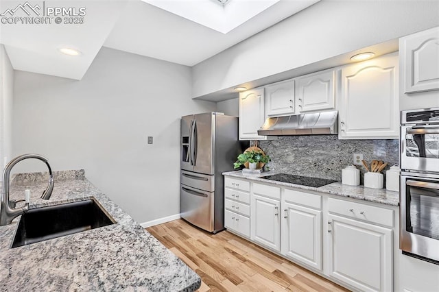 kitchen with white cabinetry, appliances with stainless steel finishes, light stone countertops, and sink