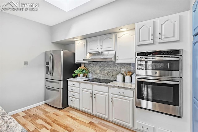 kitchen featuring light hardwood / wood-style flooring, appliances with stainless steel finishes, light stone counters, tasteful backsplash, and white cabinets