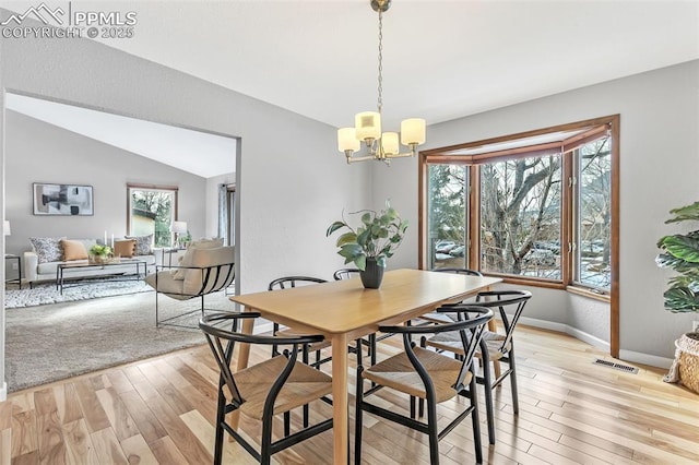 dining area with lofted ceiling, plenty of natural light, light hardwood / wood-style floors, and a chandelier