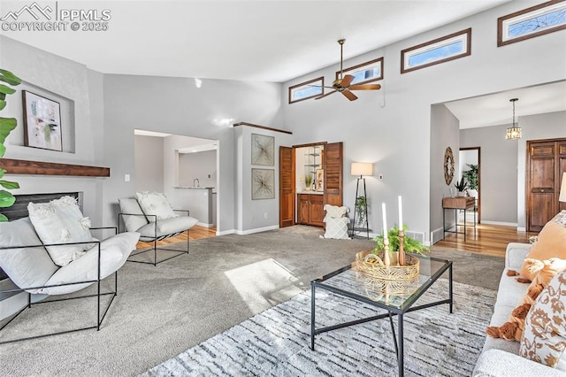 carpeted living room featuring plenty of natural light, a towering ceiling, and ceiling fan