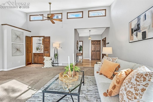 carpeted living room with ceiling fan and a high ceiling