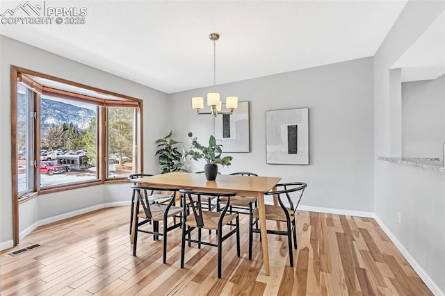 dining space with a notable chandelier and light hardwood / wood-style flooring