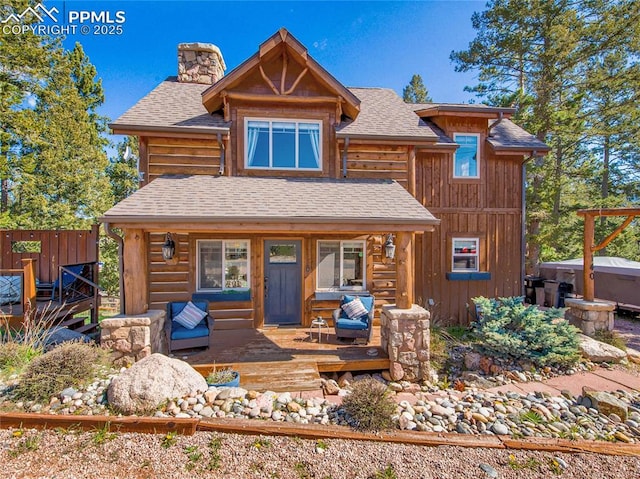 rustic home with a chimney, a deck, and roof with shingles