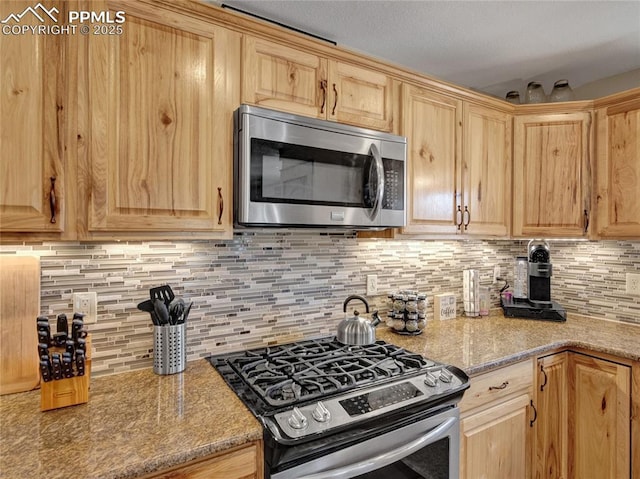 kitchen featuring appliances with stainless steel finishes, decorative backsplash, and light stone countertops