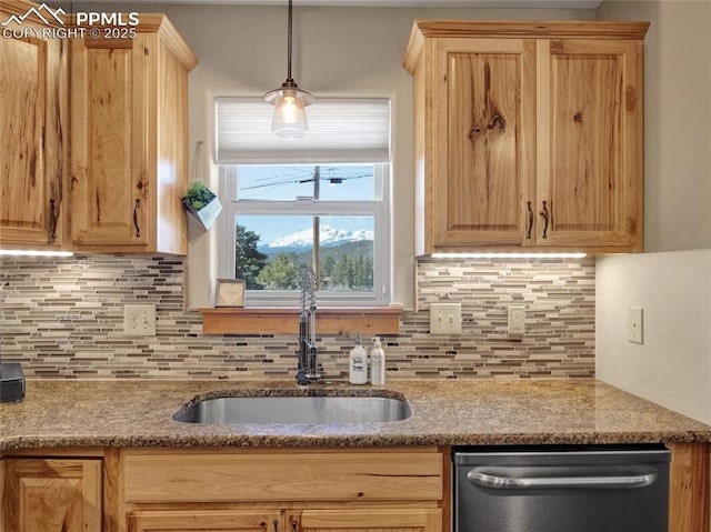 kitchen with decorative backsplash, pendant lighting, a sink, and stainless steel dishwasher