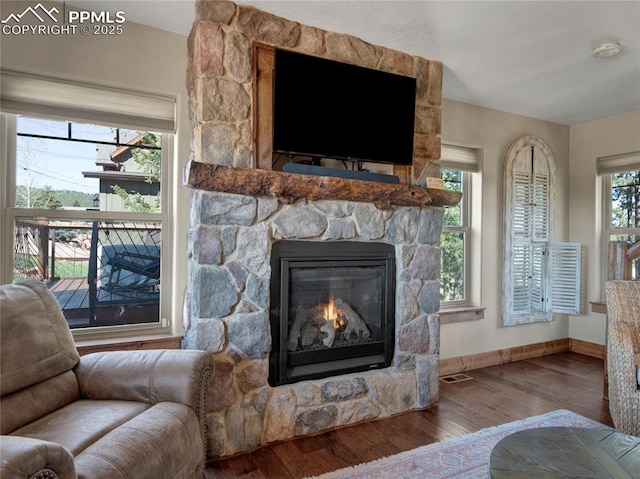 interior details featuring visible vents, a fireplace, baseboards, and wood finished floors