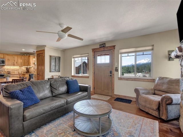 living room featuring ceiling fan, baseboards, and wood finished floors