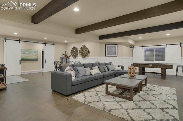 living room featuring beam ceiling, concrete floors, and a barn door