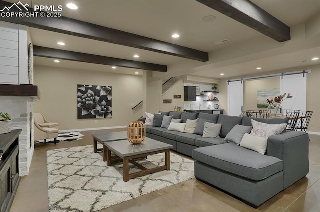 living room with a brick fireplace, beam ceiling, and a barn door